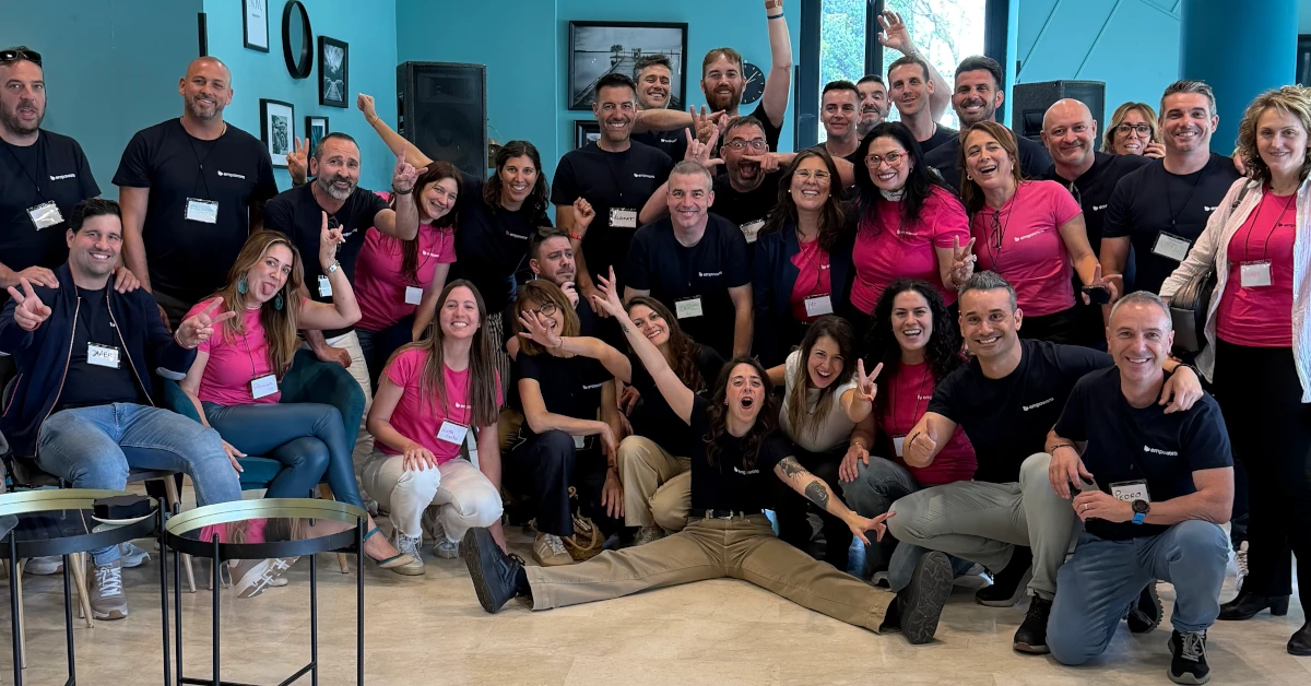 Grupo de unas cuarenta personas, equipo de empowora y clientes, sonriendo en una sala con camisetas de la marca